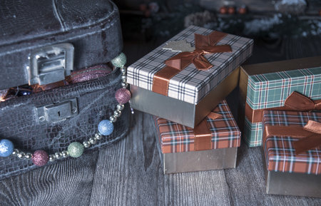 Christmas holiday background. Vintage dusty suitcase with Christmas toys and gift boxes on a dark wooden background.の写真素材