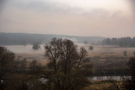 Autumn misty landscape. A thick fog rises over the river on a cloudy November day.の写真素材