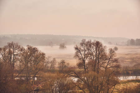 Autumn misty landscape. A thick fog rises over the river on a cloudy November day.の写真素材