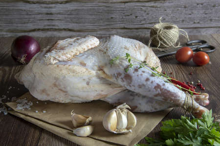 Fresh raw meat. A pale chicken carcass with seasonings and spices lies on cooking paper, ready for baking.の写真素材