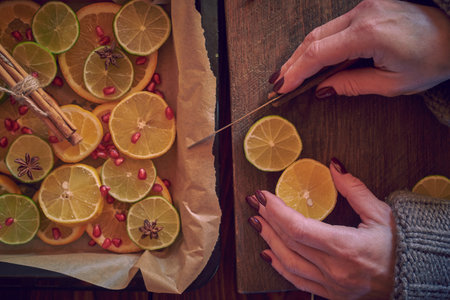 Women's hands cut citrus fruits into slices and put them on a baking sheet.の写真素材