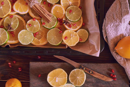 A baking tray with chopped citrus fruits and a cutting board with a knife. Food background.の写真素材