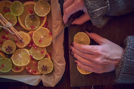 Women's hands cut citrus fruits into slices and put them on a baking sheet.の写真素材