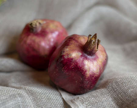 Two ripe juicy pomegranates on gray burlap. Food background.