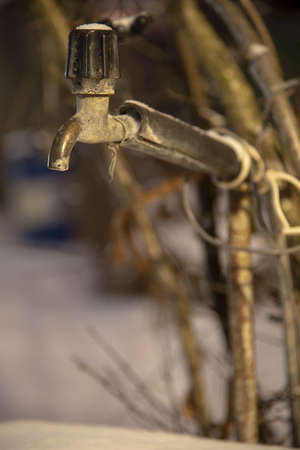 An old outdoor water tap, covered with snow.の写真素材