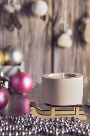 Handmade soy wax candle in a clay candlestick on the background of a New Year's decor.の写真素材