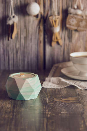 Handmade soy wax candle in a clay candlestick on the background of a New Year's decor.の写真素材