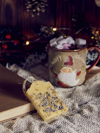 A fragrant handmade sachet made of beeswax and a mug with cocoa on the background of a New Year's decor.の写真素材