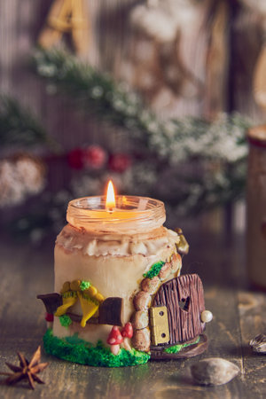 A burning handmade candle on the background of Christmas decor and mugs with cocoa and marshmallows.の写真素材