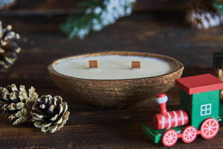One handmade candle in a coconut shell on the background of a Christmas decor.の写真素材