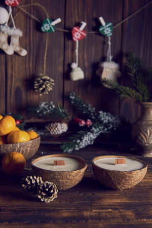 Two handmade candles in a coconut shell on the background of the Christmas decor.の写真素材