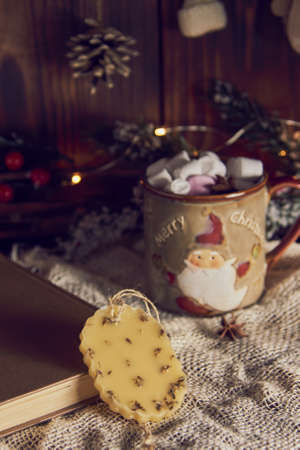 A fragrant handmade sachet made of beeswax and a mug with cocoa on the background of a New Year's decor.の写真素材