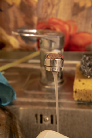 The water tap over the kitchen sink with dirty dishes. Focus on the front of the faucet.の写真素材