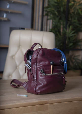 Doctor's bag. A burgundy leather backpack stands on a desk in the office, full of medical supplies.の写真素材