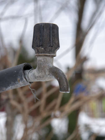 An old outdoor water tap, covered with snow.の写真素材