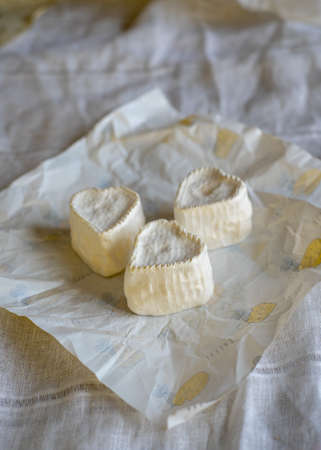 Heart-shaped cheese with white mold on wrapping paper. Home production, natural products.の写真素材
