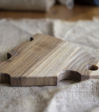 Wooden cutting board in the shape of a piece of cheese on a coarse cloth. Abstract background.の写真素材