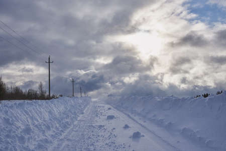 A deserted country road through snow-covered fields. Poor visibility due to a snowstorm.の写真素材
