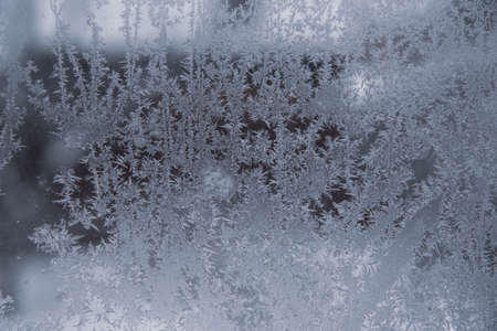 Frosty pattern on dirty window glass on a cloudy winter day. abstract background.