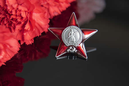 Russia, Moscow, February 2022. Day May 9 holiday background composition, Soviet order , carnation, black backdrop.のeditorial素材