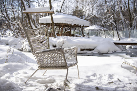A wicker chair made of painted white rattan in the snow on a clear winter day. Outdoor recreation, garden furniture.の写真素材