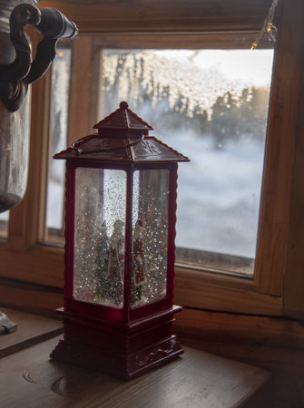 A Christmas lantern and an ancient samovar on a wooden table against the background of a window.の写真素材