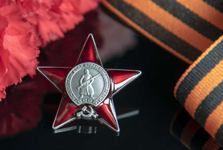 Russia, Moscow, February 2022. Day May 9 holiday background composition, Soviet order ,St. george's ribbon, carnation, black backdrop.のeditorial素材