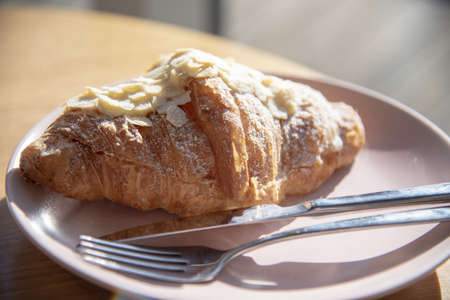 Almond sweet croissant on a plate on the table in a cafe.の写真素材
