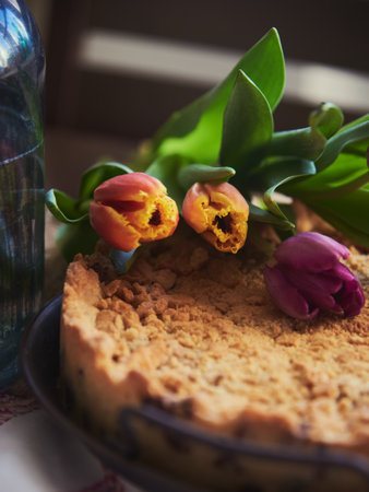 Homemade cake sprinkled with cookie crumbs on a metal vintage dish, decorated with tulips. Food background.の写真素材