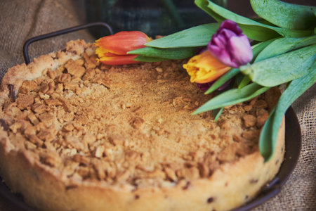 Homemade cake sprinkled with cookie crumbs on a metal vintage dish, decorated with tulips. Food background.の写真素材