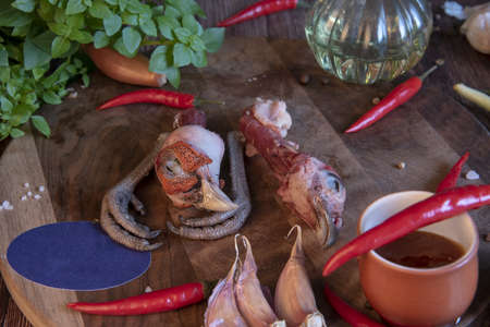 Severed heads and paws of a pheasant on a cutting board surrounded by spicy herbs and various spices. symbolizing meat industry and butcher.の写真素材