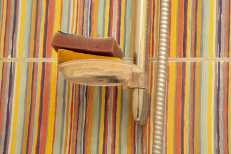 Dirty used sponges in a stand against a striped wall.の写真素材