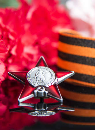 Russia, Moscow, February 2022. Victory Day May 9 holiday background composition, Soviet order, carnation, St. George ribbon, black backdrop.のeditorial素材