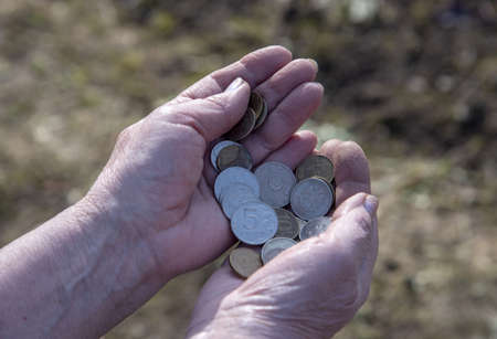 A pensioner woman counts small money in her hands.の写真素材