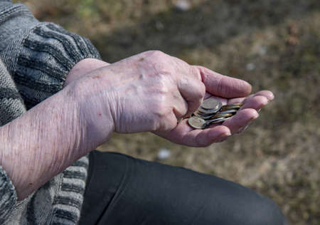 A pensioner woman counts small money in her hands.の写真素材