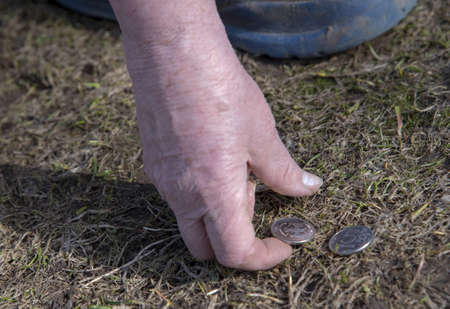An elderly woman picks up a ruble coin from the ground.の写真素材