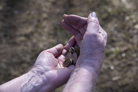 A pensioner woman counts small money in her hands.の写真素材
