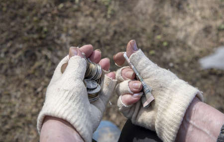 An elderly woman in dirty gloves holds small ruble coins.の写真素材