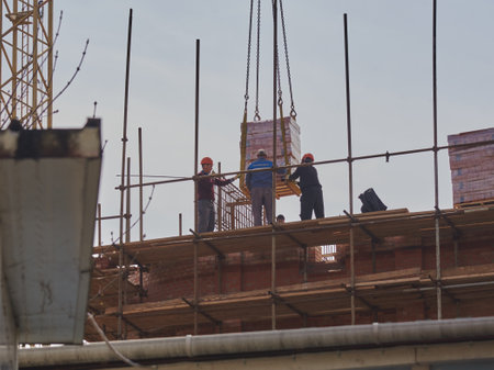 Russia, Moscow, April 2022. Workers at the construction site take a load of bricks.のeditorial素材