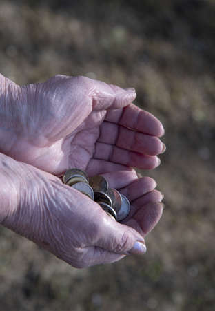 A pensioner woman counts small money in her hands.の写真素材
