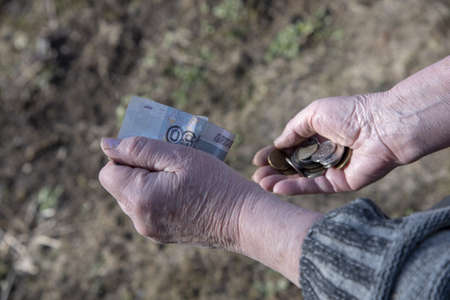 A pensioner woman counts small money in her hands.の写真素材