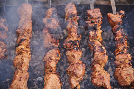 Delicious pork kebab on skewers on the grill, shrouded in smoke.