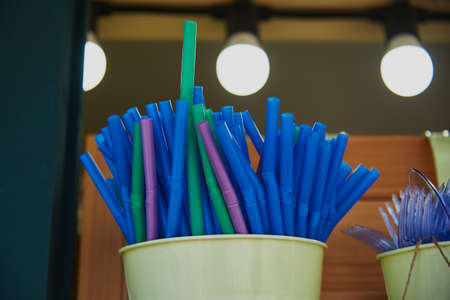 There are a lot of plastic tubes for drinks in a metal bucket on the bar counter in an outdoor cafe.の写真素材