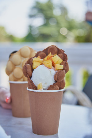 Waffles with ice cream, fruit and chocolate in cardboard disposable cups.