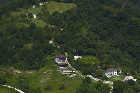 Summer mountain landscape. Mountains covered with green grass and trees, dirt roads and residential buildings.の写真素材
