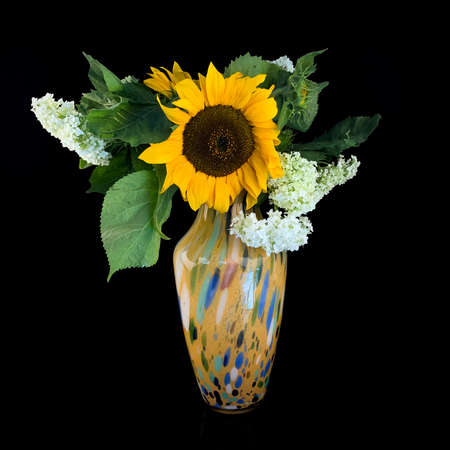 antique yellow porcelain vase with a bouquet of flowers on a black isolated background. ceramic vase with flowersの写真素材