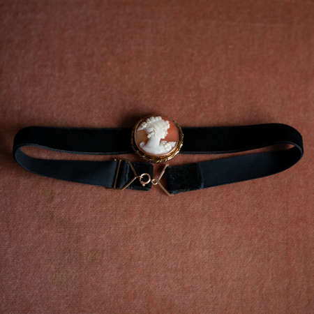 antique choker with medallion in gold frame. antique brooch with a female profile. vintage choker on black isolated backgroundの写真素材