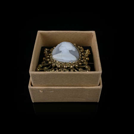 antique jewelry. antique brooch with a female profile in a gold frame. vintage brooch on a black isolated backgroundの写真素材