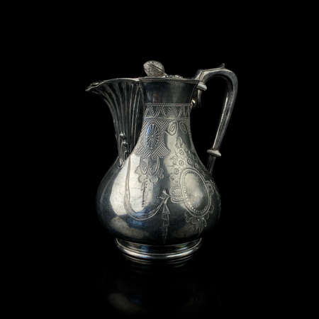 antique metal milk jug. metal jug with engraving on a black isolated backgroundの写真素材