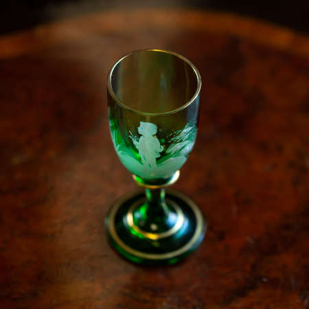 green glass wineglass in luxury interior. green glass with engraving close-up. bohemian glass closeupの写真素材